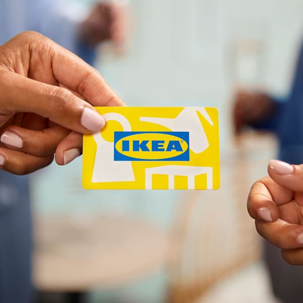 Käsi ojentaa IKEA-lahjakorttia, jota toinen käsi ojentuu vastaanottamaan.