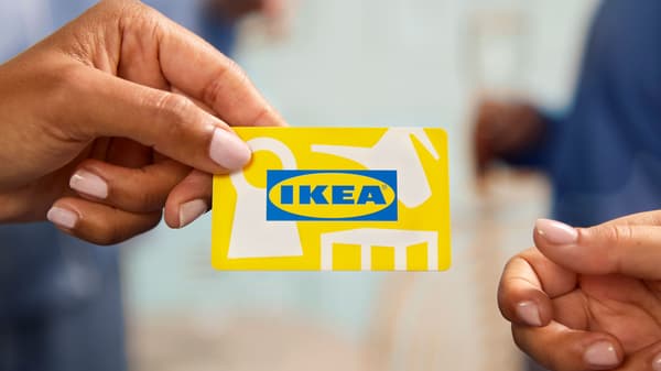 Käsi ojentaa IKEA-lahjakorttia, jota toinen käsi ojentuu vastaanottamaan.