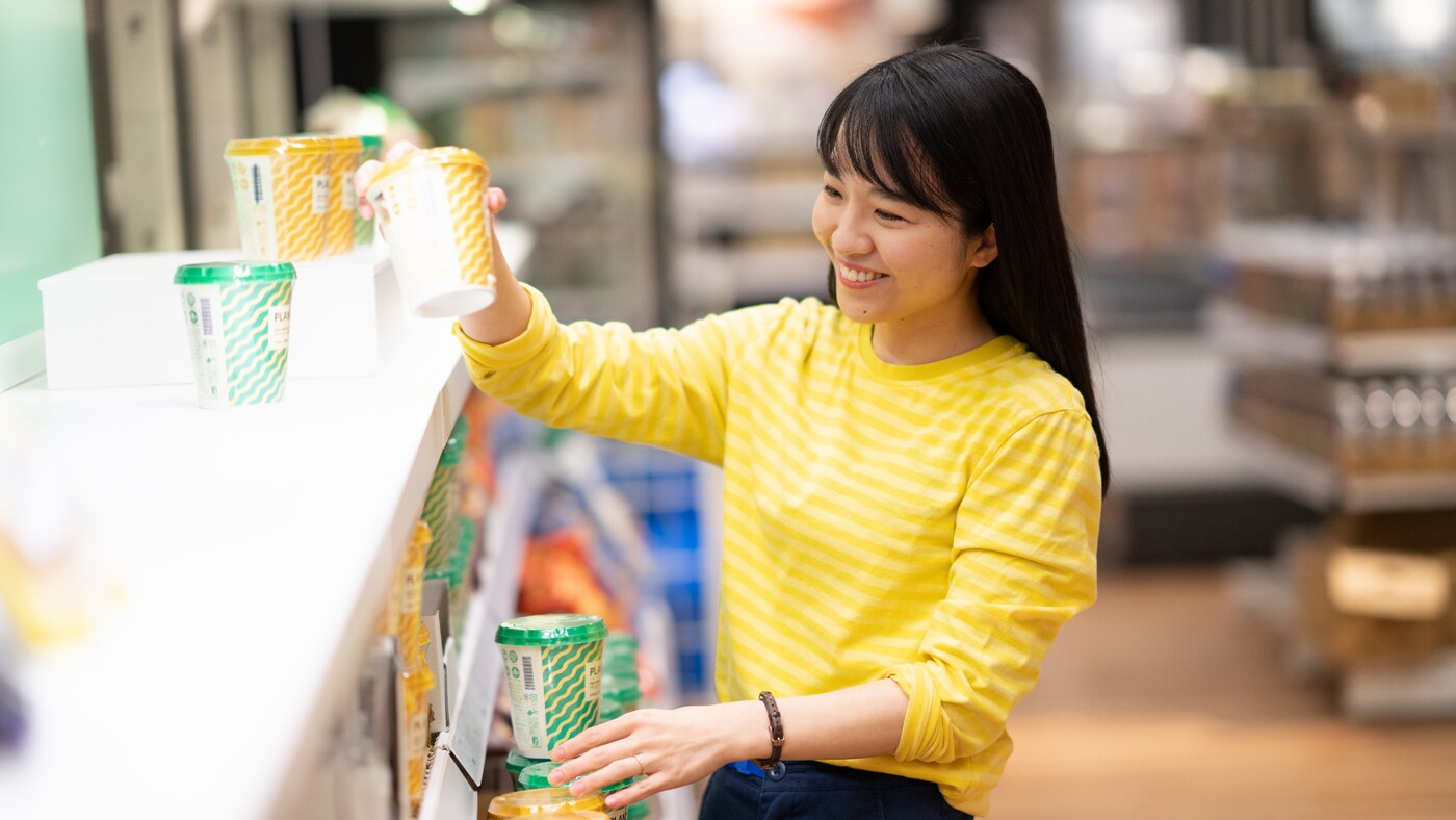 カフェ風カウンターでドリンクを準備するスタッフ。明るい店内とカラフルなカップが並ぶ様子。