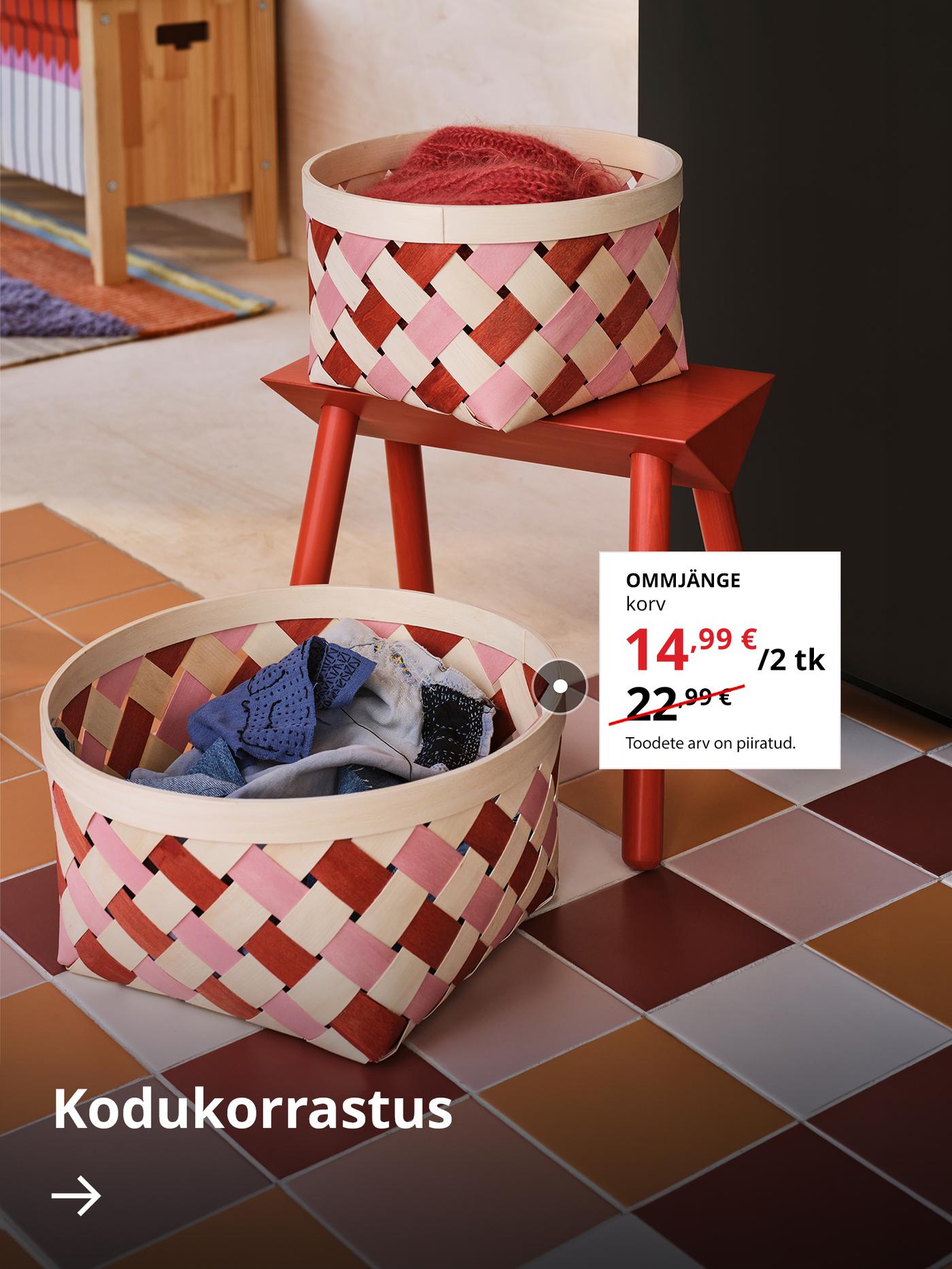 Kaks punaste ja roosade detailidega paplipuust punutud OMMJÄNGE korvi, mis on asetatud põrandale. Nende kõrval valgel taustal on kuvatud väljamüügi erihind 14,99 € (tavahind 22,99 €). All on nool tekstiga „Kodukorrastus”.
