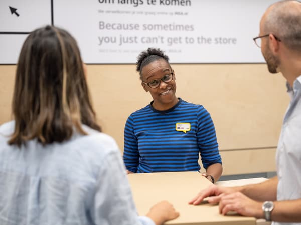 Kaksi asiakasta ovat keskustelemassa sinipaitaisen IKEA-työntekijän kanssa tavaratalon asiakaspalvelupisteellä.
