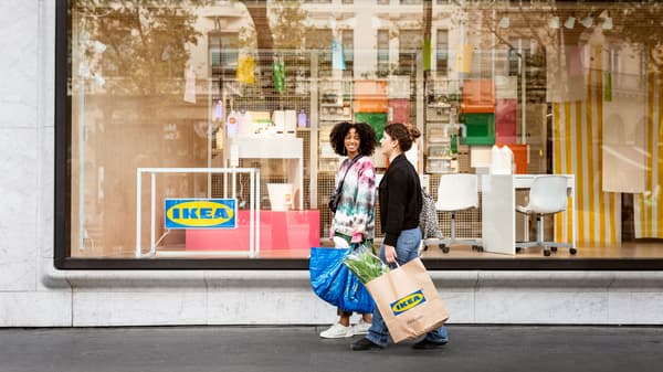 Kaksi naista kävelee IKEA-suunnittelustudion editse käsissään IKEA-kasseja.