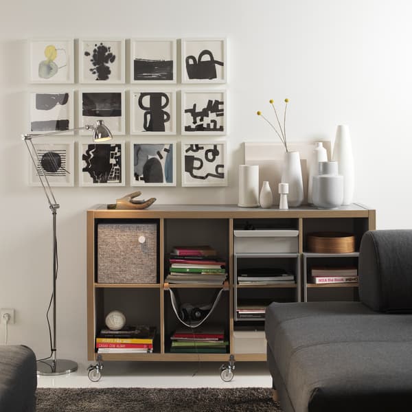 วางแนวตั้งเป็นชั้นวางของ หรือวางแนวนอนและวางโต๊ะข้างไว้ด้านบน ลองชั้นวางของ KALLAX/คอลแล็กซ์ สีเทา/ไม้ ของอิเกีย