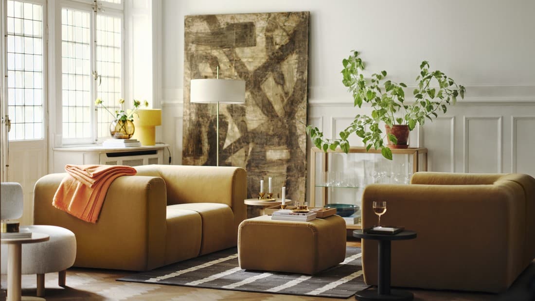 Kalustettu olohuone, jossa vaaleanruskea sohva, nojatuoli ja rahi