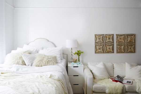Kamer met veel witte meubels en twee schildeijen met vormpjes die aan de muur hangen.