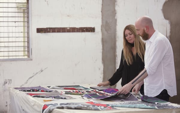Karin Gustavsson and Martin Bergström looking at colourful fabrics on a large table.