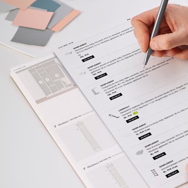 Kartki z wydrukiem projektu szafy PAX i listą zakupów, na których kobieta nanosi notatki.