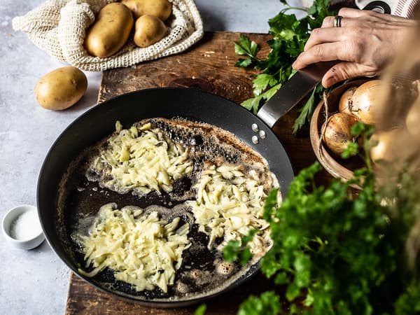 Kartoffel-Zwiebel-Rösti werden in einer Pfanne angebraten.