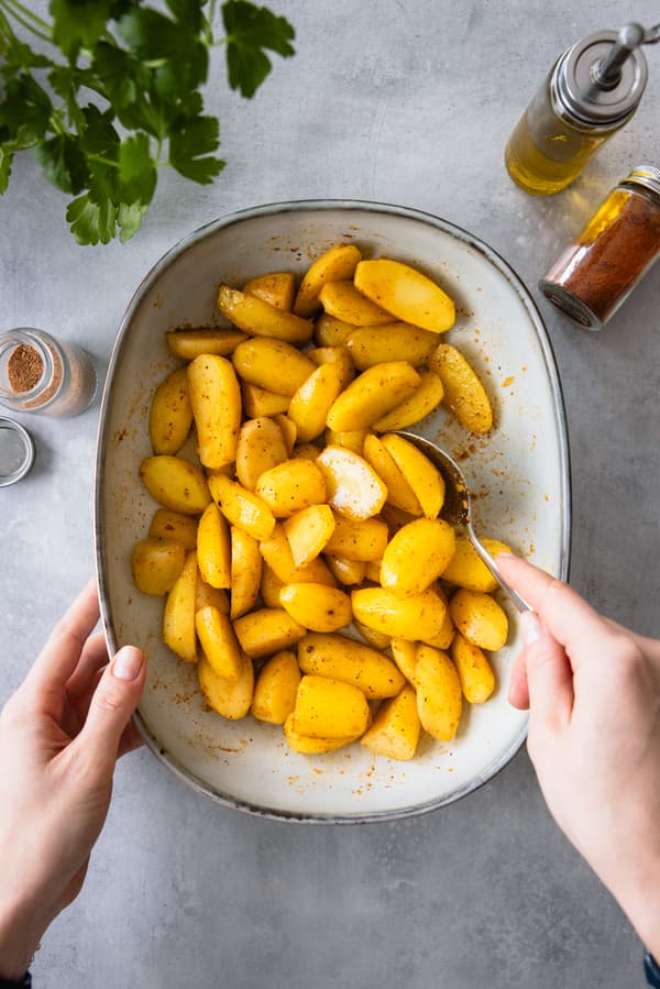 Kartoffeln werden in eine Auflaufform gegeben.