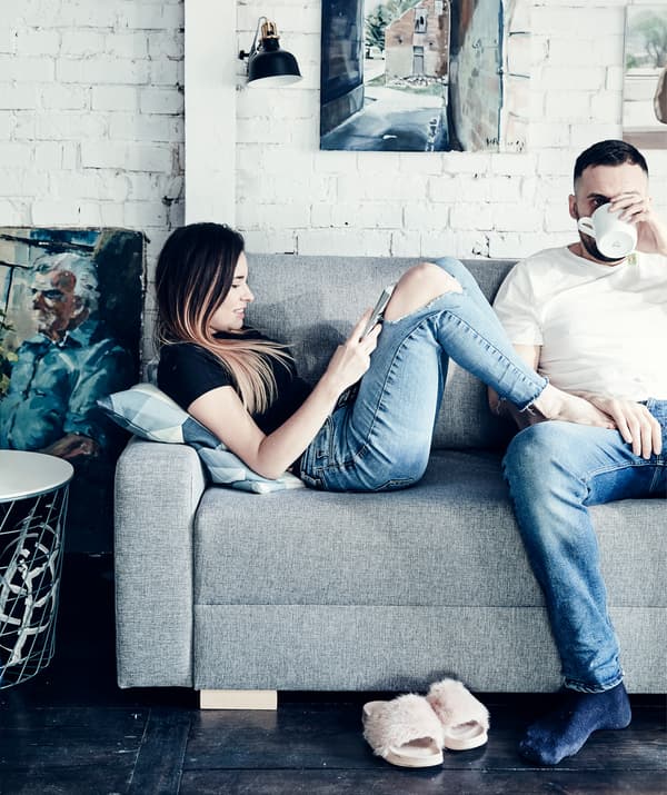 Katarzyna et Mikolaj se relaxant sur leur canapé gris.