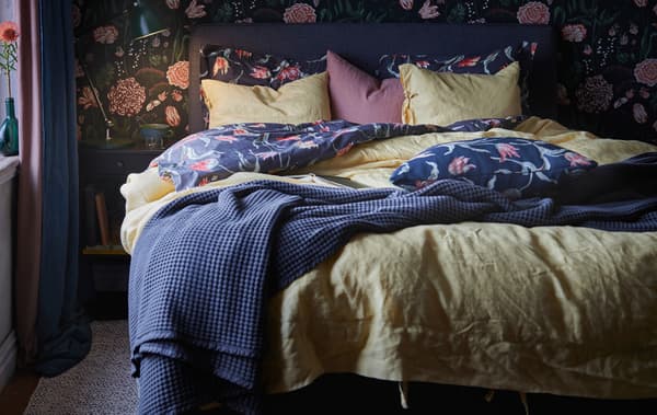 Katil yang selesa dengan dua duvet, bantal dan alas katil. Di sebelahnya terdapat meja sisi katil dengan lampu yang dinyalakan dan koleh.