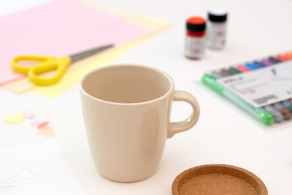 Keramik tasse steht auf einem Tisch mit Bastelutensilien.