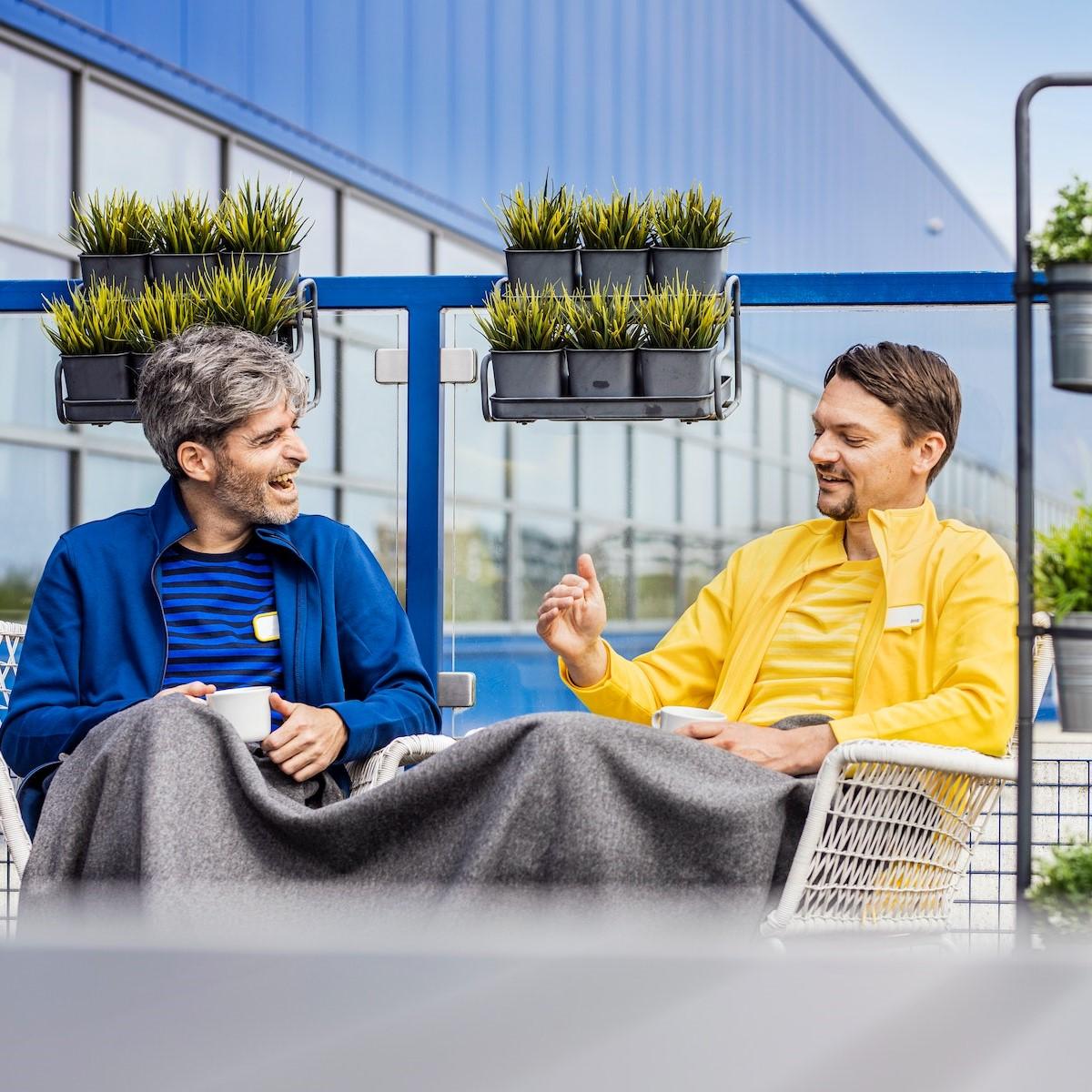 Két IKEA munkatárs a teraszon kávézik és beszélget.