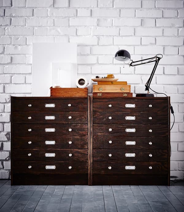 Két IKEA RAST irodai szekrény egy fehér téglafal elé állítva. Házilagos megoldással úgy alakították át, mintha régi irattartó szekrények lennének.