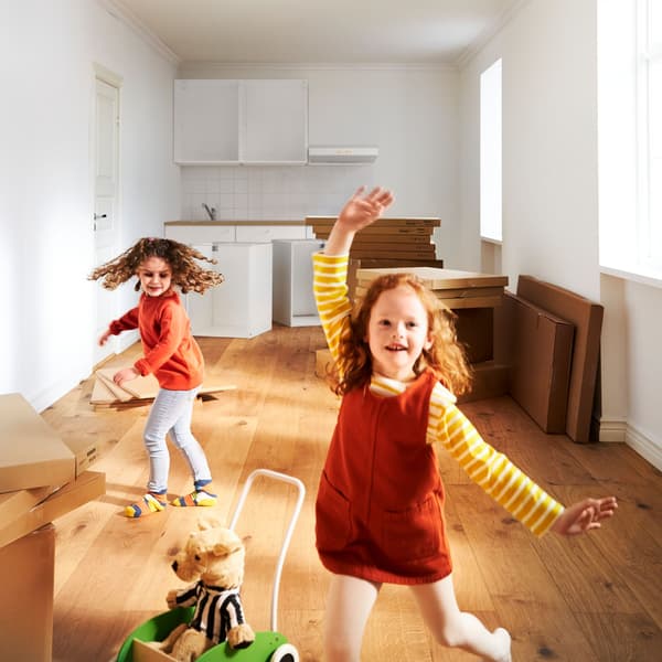 Két kislány táncol egy beépítés alatt álló konyhában.