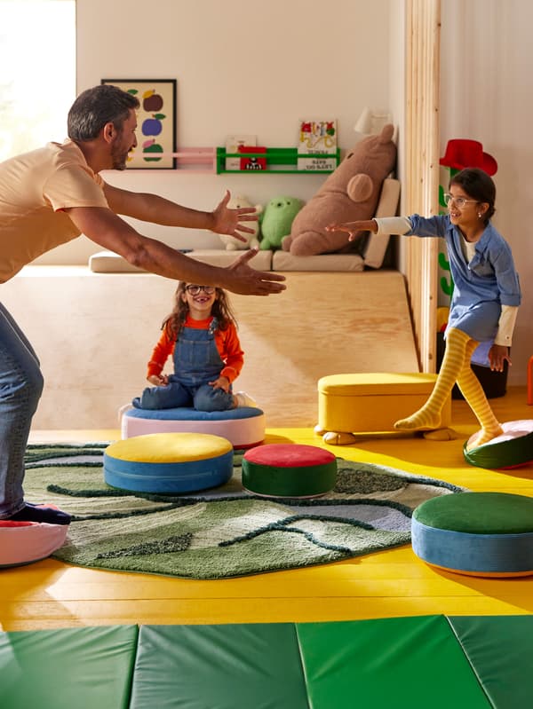 Két lány és az édesapjuk a GREJSIMOJS ülőpárnákon lépdelve játszanak.