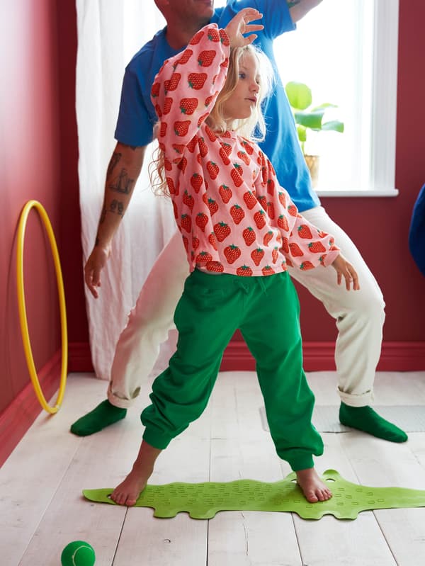 Ketten tornáznak; a szemben lévő lány egy zöld krokodil formájú PATRULL csúszásgátlón áll.