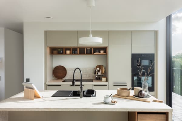 Keuken met lichtgroene STENSUND fronten, zwarte GRUNDAD inductiekookplaat en wandgemonteerde MATTRADITION afzuigkap.