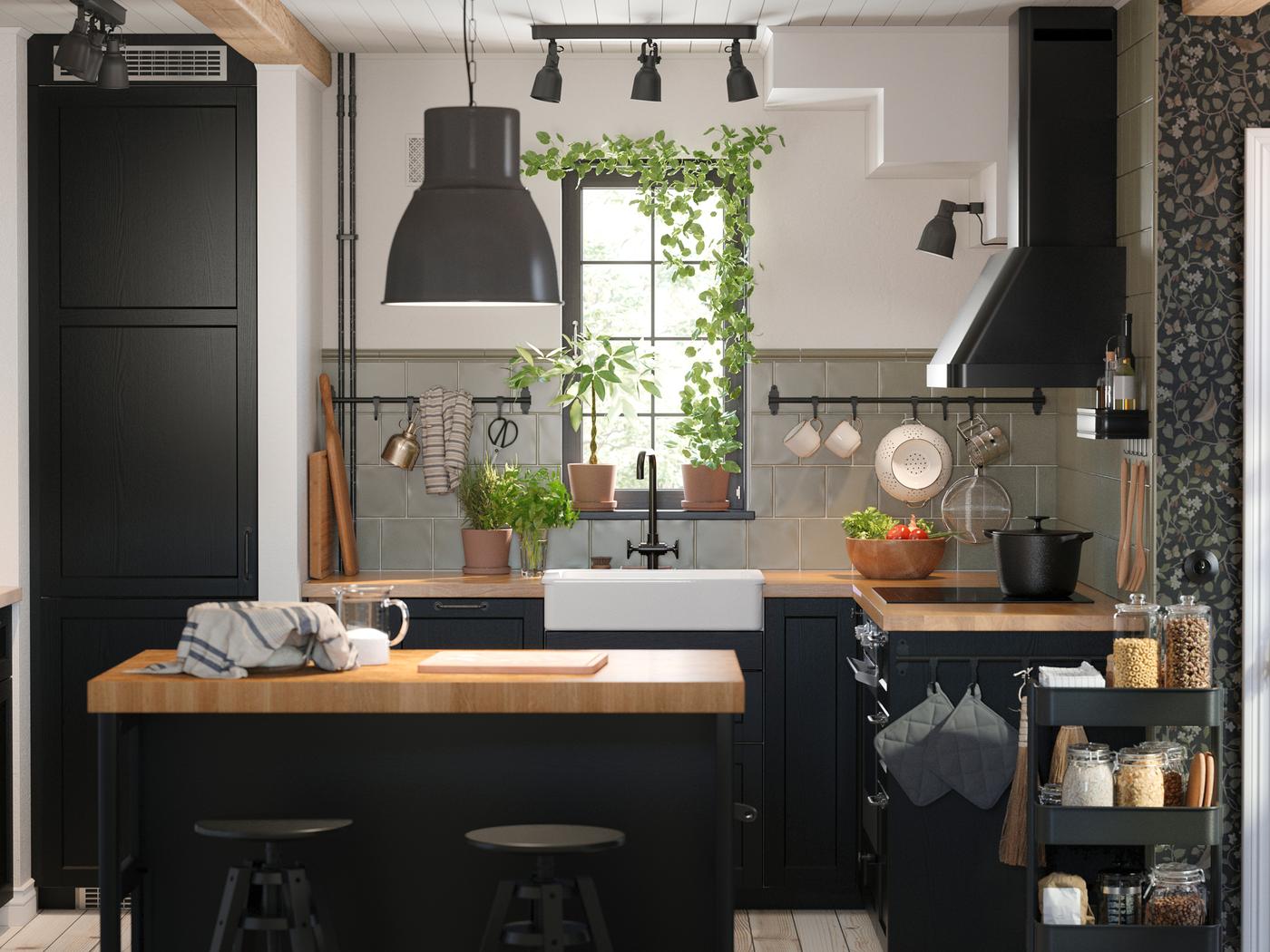 Keuken met zwartgebeitste LERHYTTAN fronten, KARLBY werkbladen in eiken/fineer en een HEKTAR hanglamp in donkergrijs.