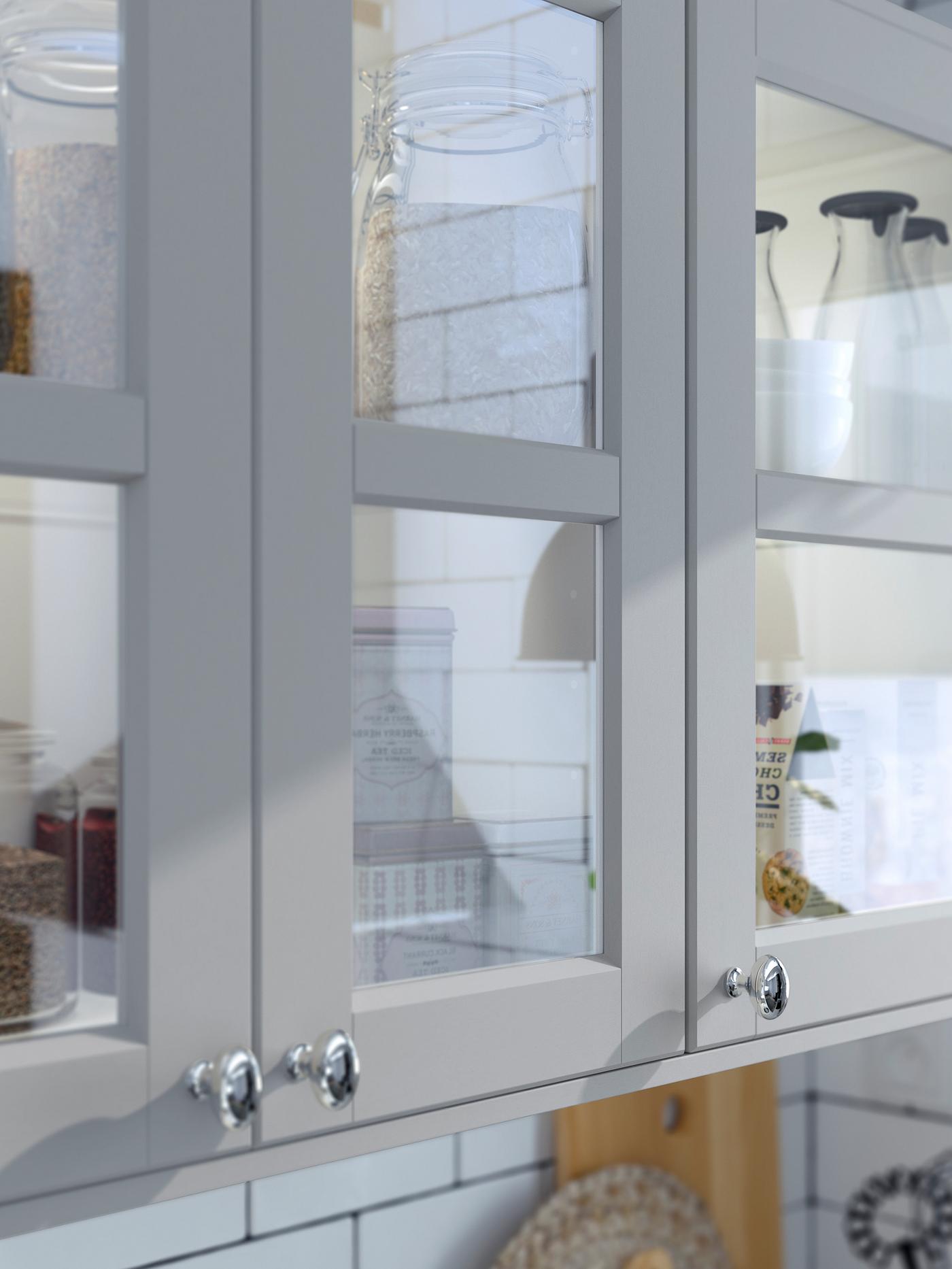 Keukenkasten met drie deuren van gehard glas en lichtgrijze houten frames met afgeschuinde hoeken.