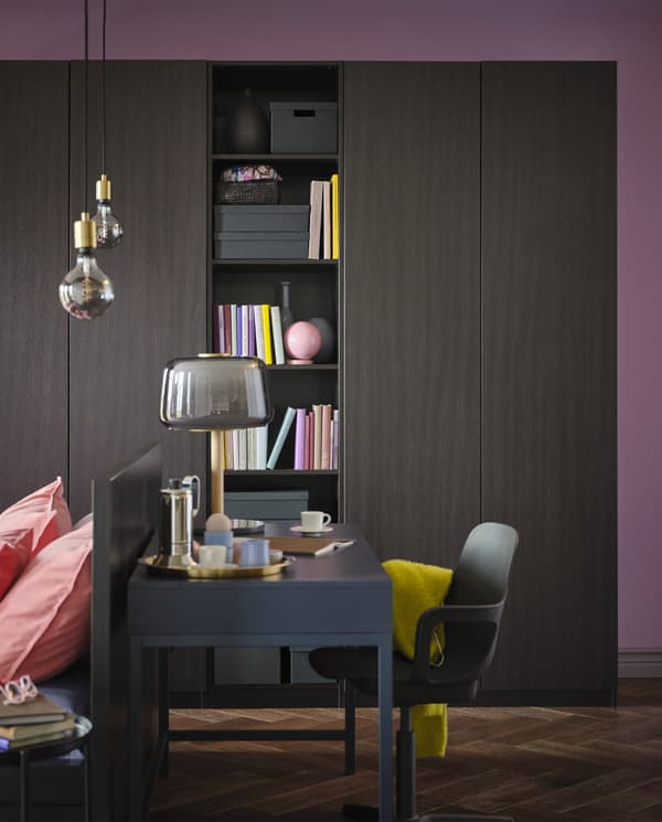 خزانة ملابس PAX/FORSAND أسود-بني مع قسم مفتوح به كتب. وفي الأمام يوجد مكتب أزرق وكرسي أسود.