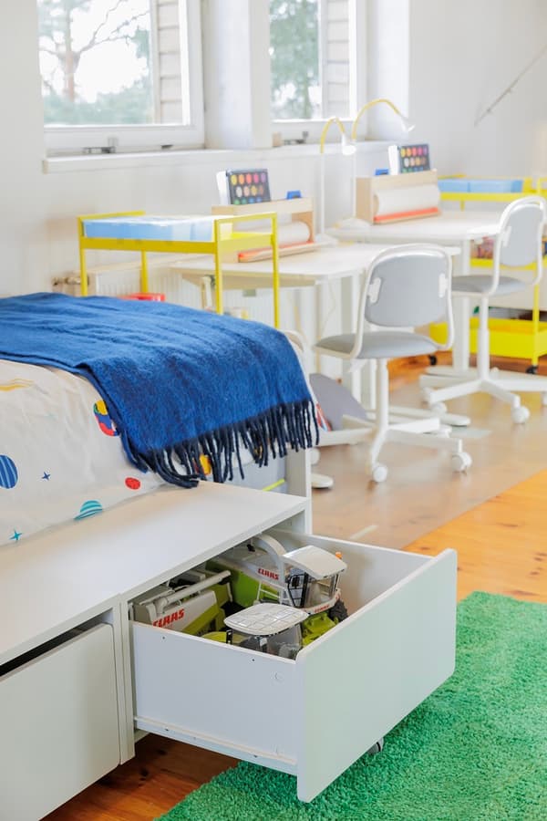 Kids bed with storage drawer and study desks in bright room