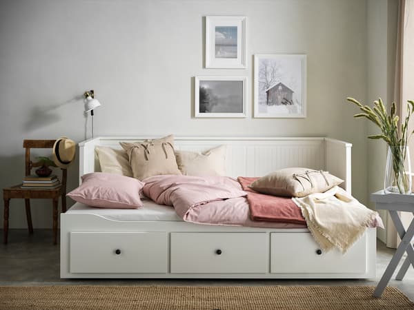 収納付き白いベッドにピンクのクッションを合わせた機能的な寝室。シンプルで温かみのある空間。