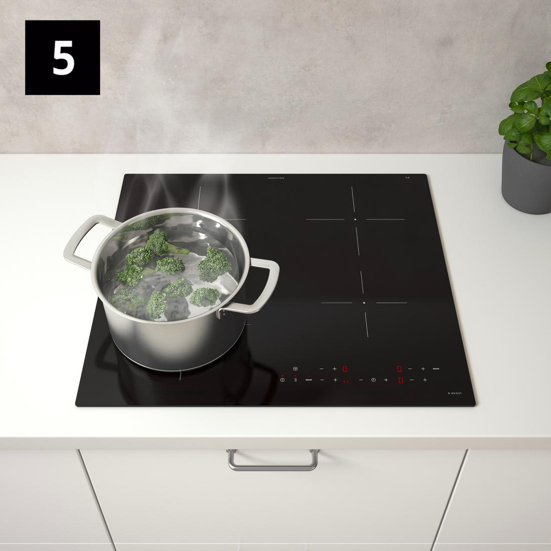 Kilátás egy fekete tűzhelyre, amelyen egy edényben brokkoli fő.