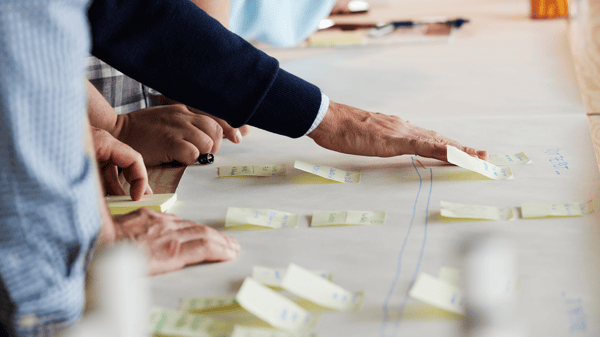 大きな紙に文字の書かれた付箋を張り付けている