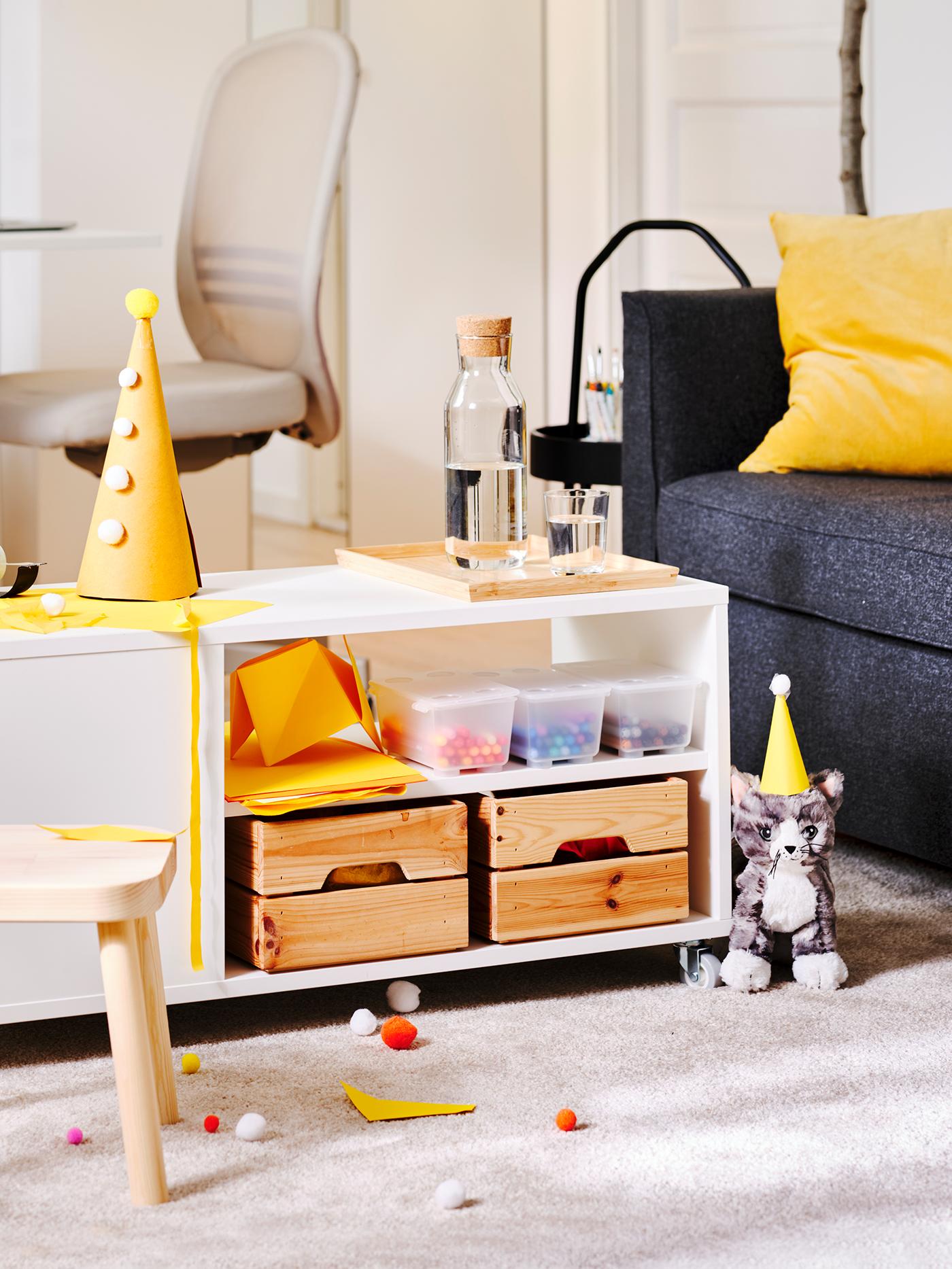 Kinder knutselhoek met feesthoedjes, speelgoed en opbergplanken in een gezellige woonkamer.