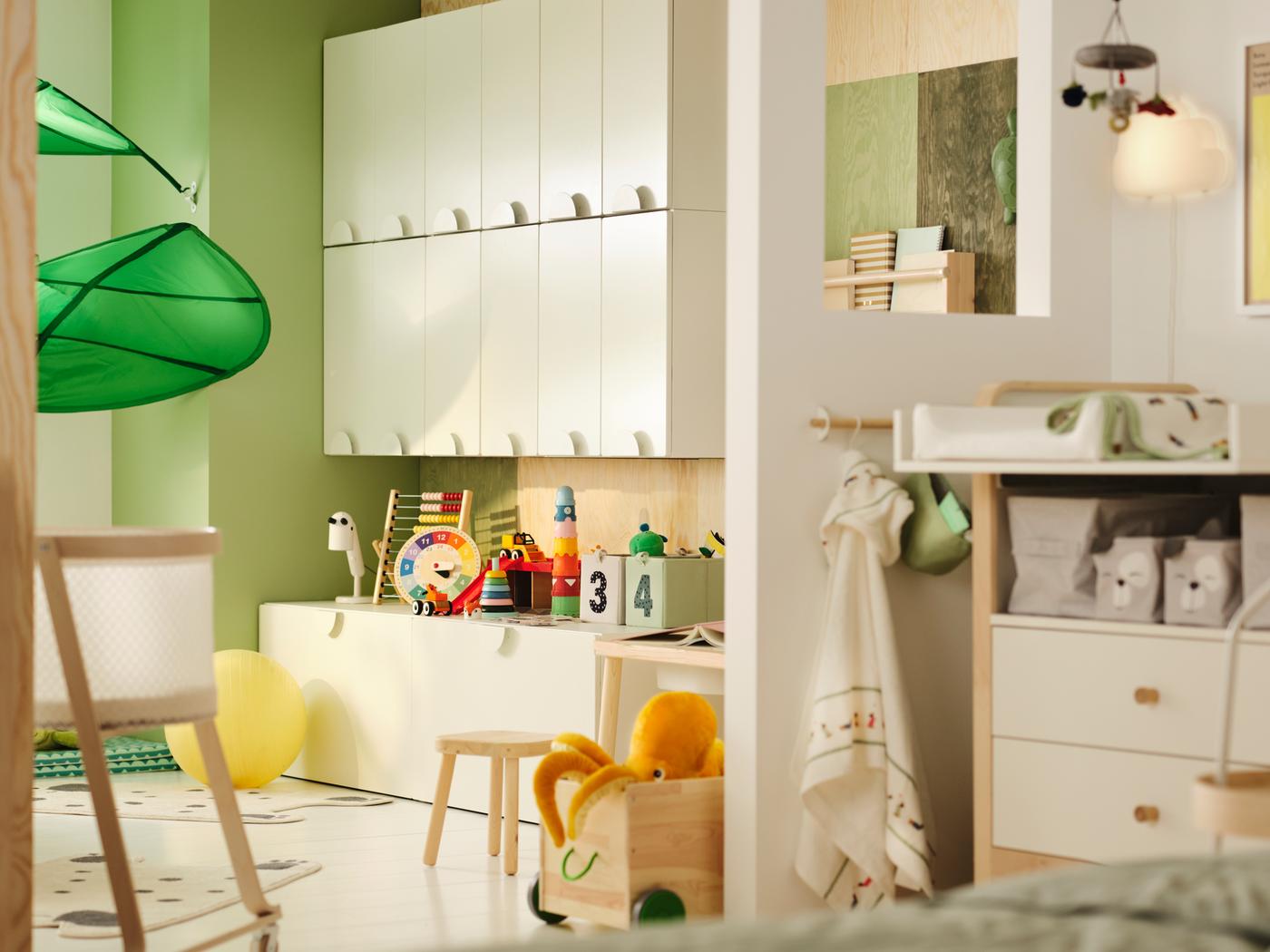 Kinderkamer met gedeeltelijke tussenwand als scheiding. Aan één kant zien we SMÅSTAD kasten en speelgoed, aan de andere kant een verschoonruimte.