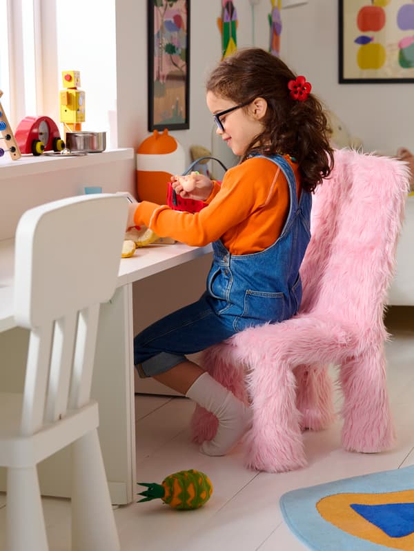Kislány, aki egy rózsaszínű GREJSIMOJS gyerekszékhuzattal kiegészített MAMMUT széken ül.