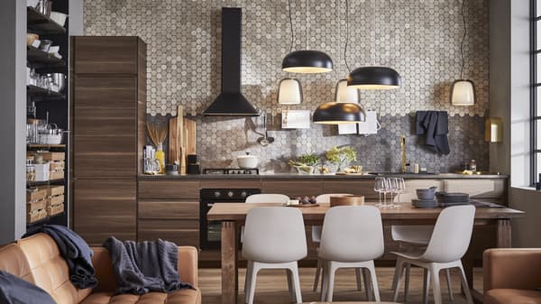 Kitchen against a brick wall, it has brown cabinet doors and a black stove vent