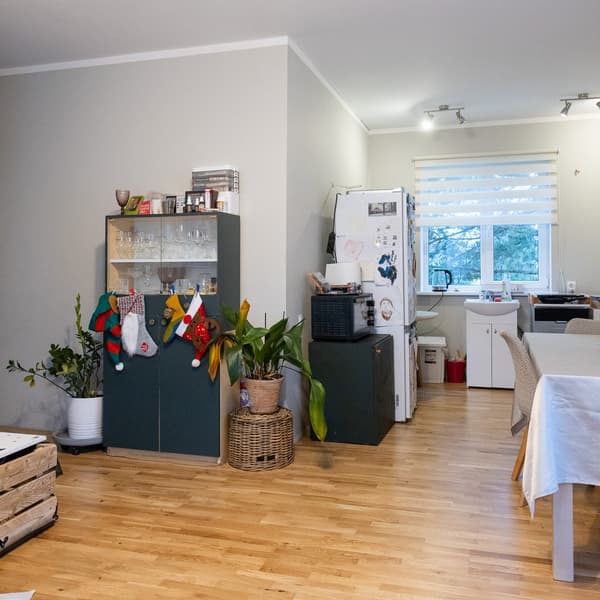 Kitchen before the makeover with open shelving, a dining table and children’s items in the corner; a bright space with wooden flooring and an open view into the adjoining rooms.