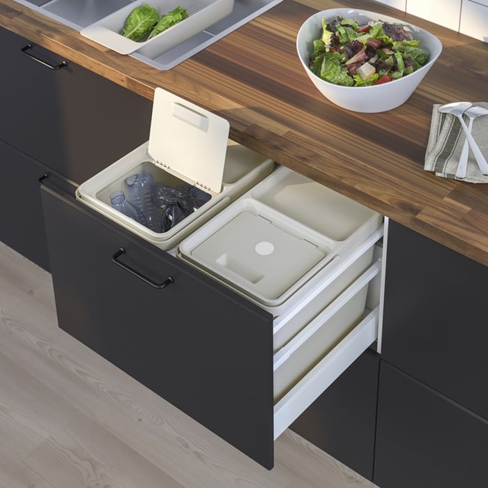 Kitchen drawer with open built-in recycling bins beneath a wooden worktop.