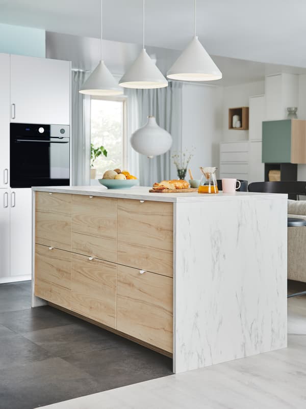 Kitchen island, one side made up of large ASKERSUND drawer fronts, in the kitchen area of an open floor-plan interior.