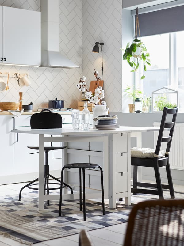 Kitchen where a white NORDEN gateleg table, both leafs out, is surrounded by odd seating, including a KULLABERG chair.