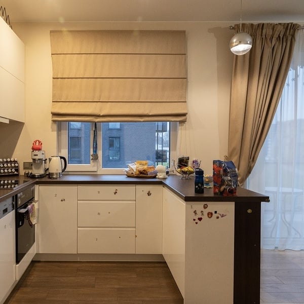 Kitchen with white cabinets, brown countertop, and large window.