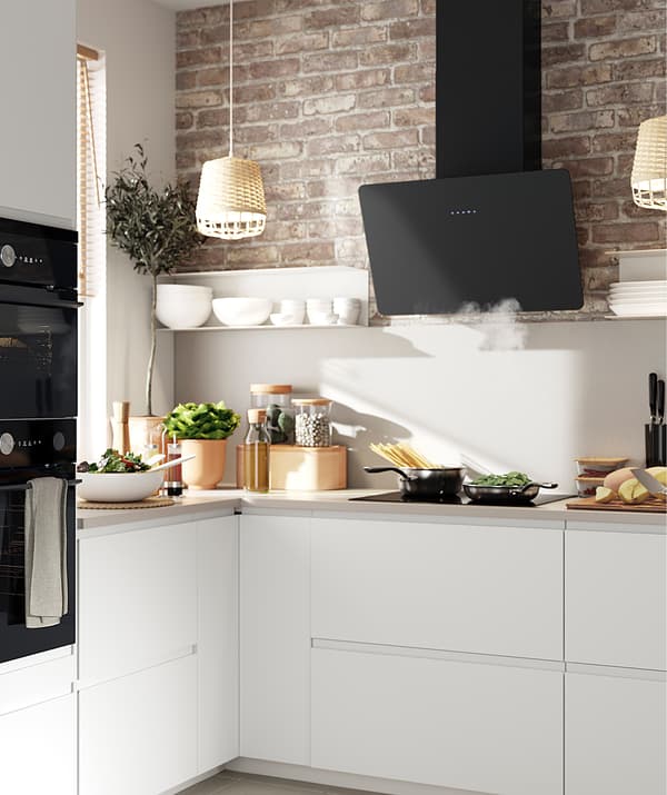 Kitchen with white cupboards, an extractor hood and a brick wall