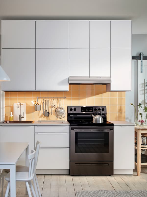 Kitchen worktop with sink, hob and utensils framed above and below with rows of white-front SEKTION cabinets.