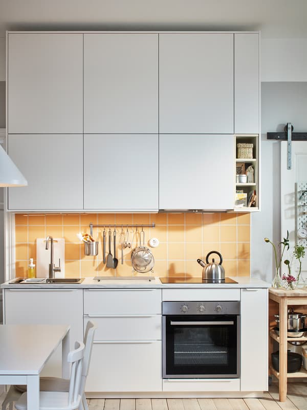 Kitchen worktop with sink, hob and utensils framed above and below with rows of white-front METOD cabinets.