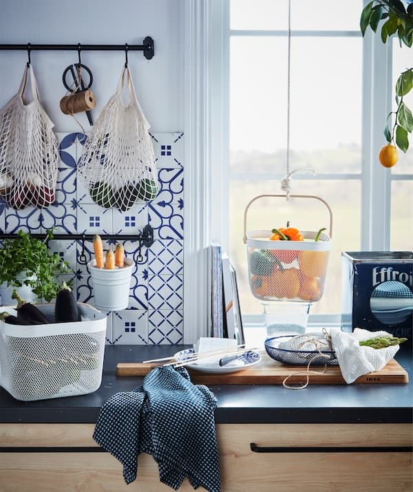 Kitchen worktop with various food produce kept in hanging and standing containers.