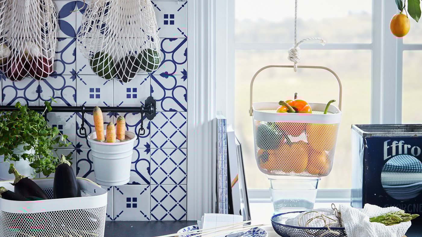 Kitchen worktop with various produce kept in hanging and standing baskets, like KUNGSFORS nets and RISATORP baskets.