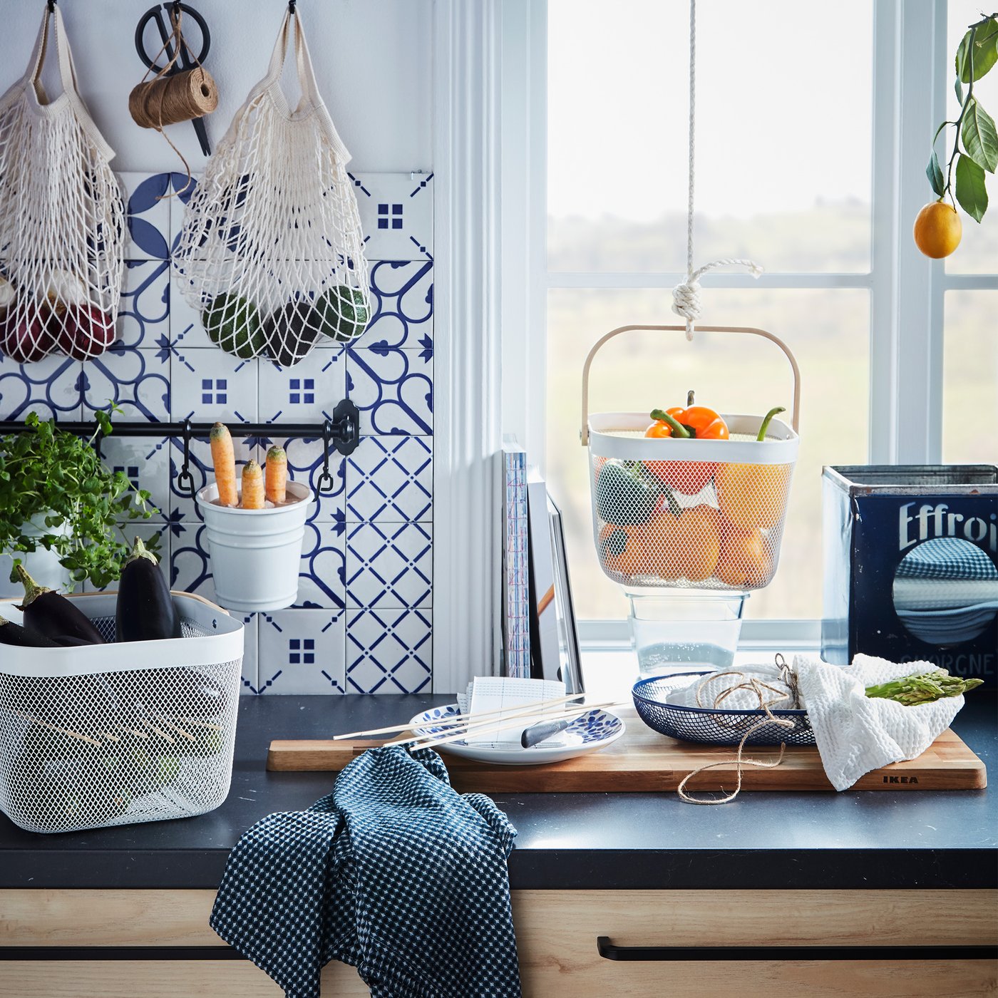 Kitchen worktop with various produce kept in hanging and standing containers, like KUNGSFORS nets and RISATORP baskets.