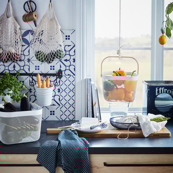 Kitchen worktop with various produce kept in hanging and standing containers, like KUNGSFORS nets and RISATORP baskets.