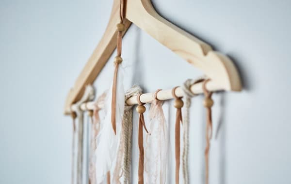 Kleiderbügel aus Holz an einer Wand mit vielen Schnüren daran befestigt.