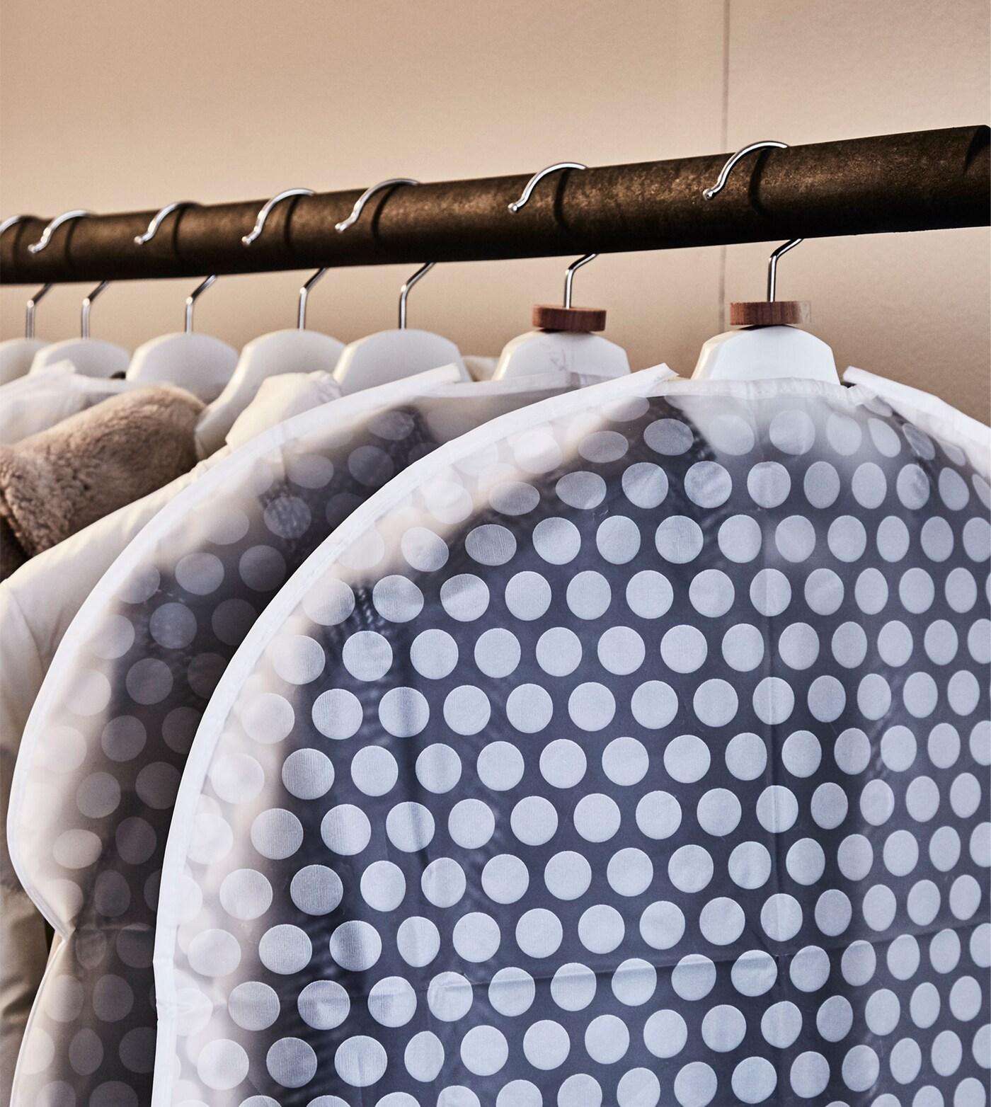 Kleidung an einer Kleiderstange in der transparenten PLURING Kleiderschutzhülle in Weiß.