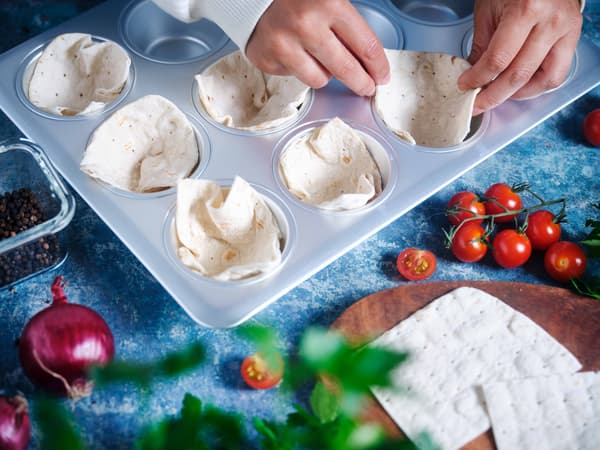 Kleine Fladenbrote werden in einer Muffinform platziert.