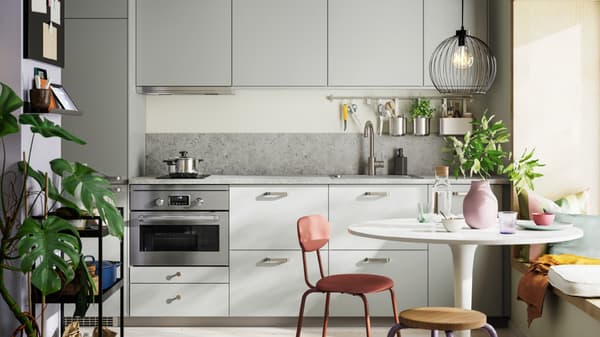 Kleine keuken op één lijn met lichtgrijze HAVSTORP fronten is afgewerkt met een kleurrijke eetruimte en groene planten.