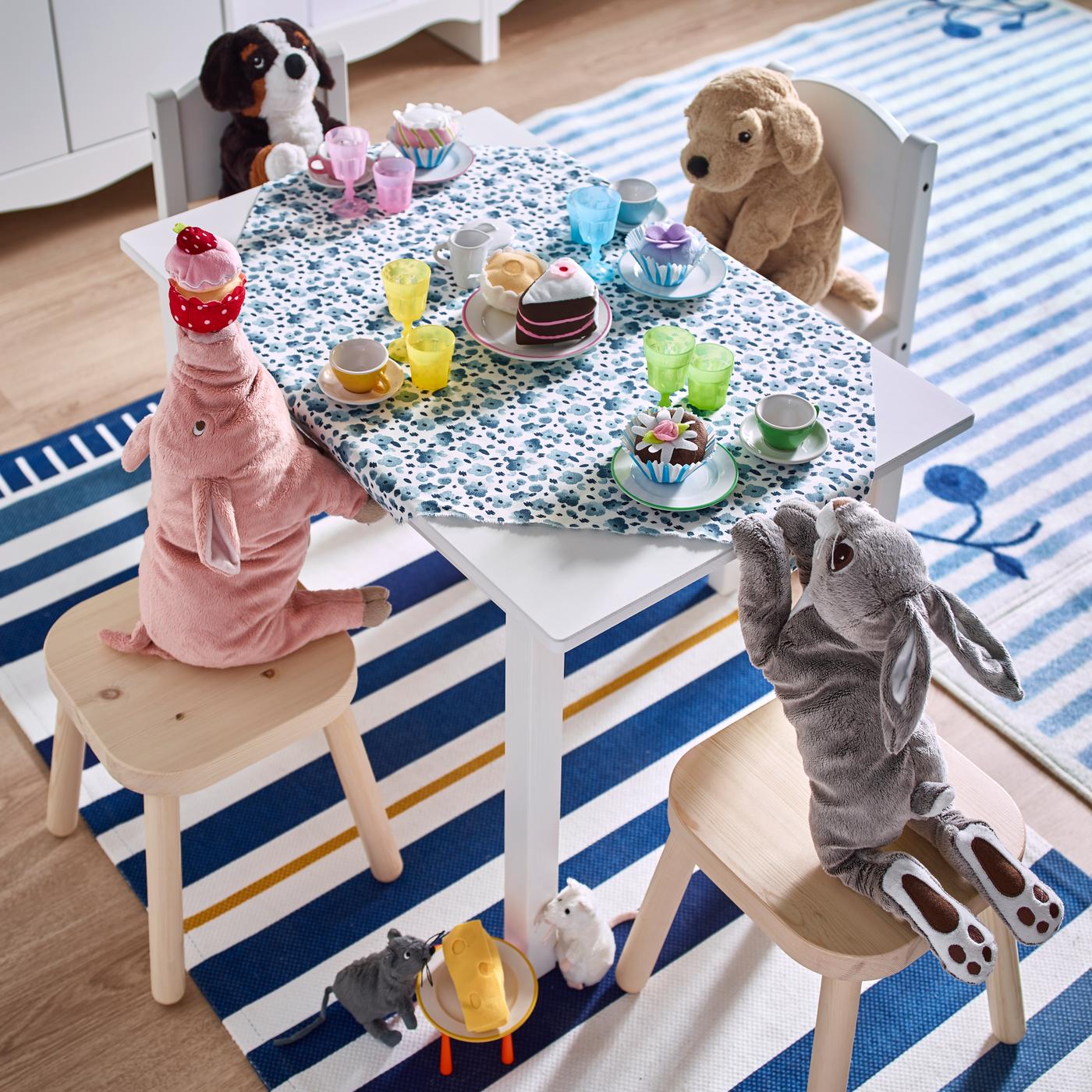 Knuffels zitten aan een tafel op stoelen en krukjes